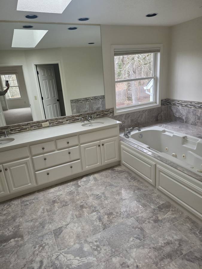 Bathroom with a wide white vanity, bathtub and tile floor